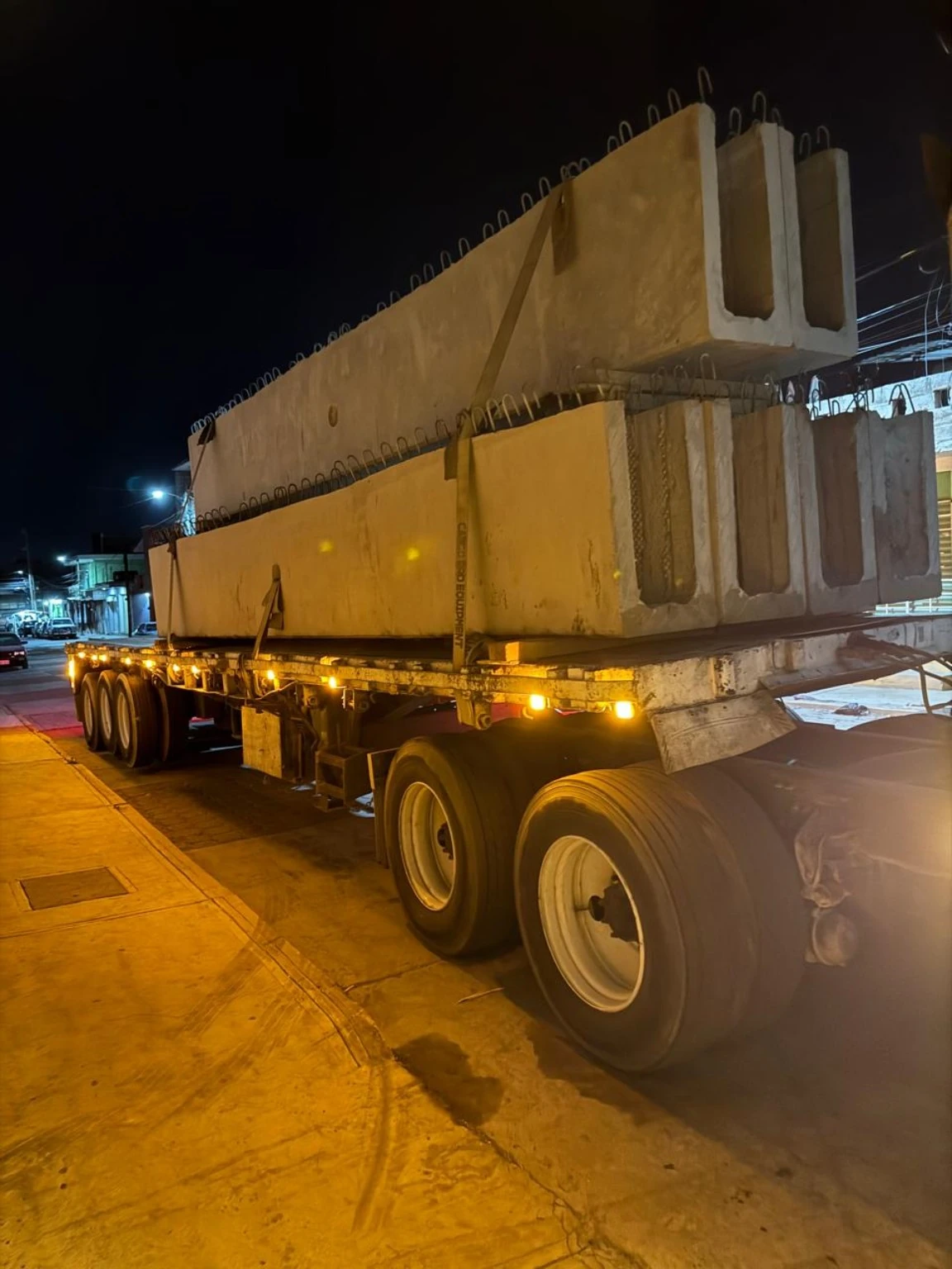 Elementos prefabricados de concreto transportados sobre plataforma durante la noche